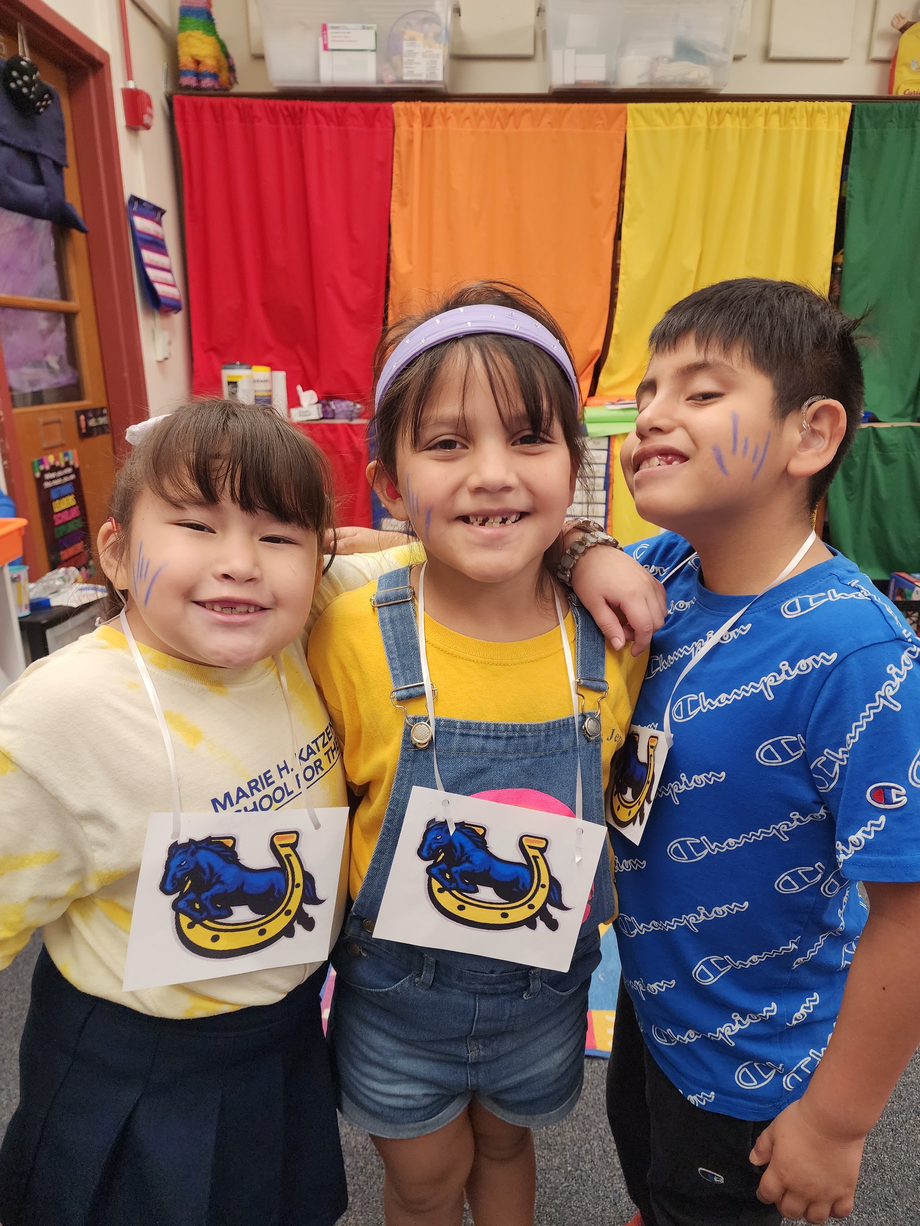 elementary students 2 girls one boy smiling with ILY face paint